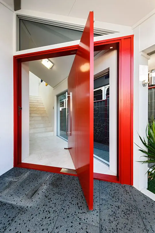 a fantastic red pivot door with a large handle is a gorgeous color statement and its design adds even more interest to the space