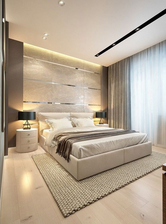 a gorgeous contemporary bedroom with a tile and metallic line accent wall, a neutral upholstered bed, round white nightstands, black lamps and several layers of light
