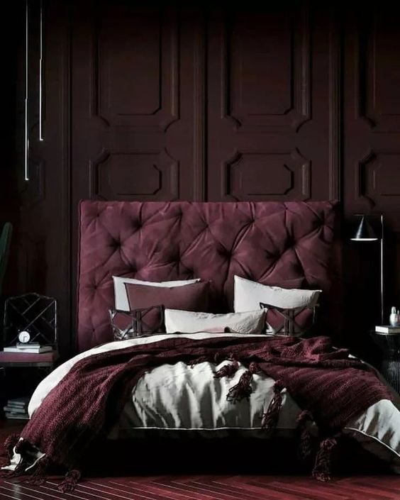 a jaw-dropping moody bedroom with a deep purple paneled wall, a purple upholstered bed, mismatching nightstands and purple and white bedding