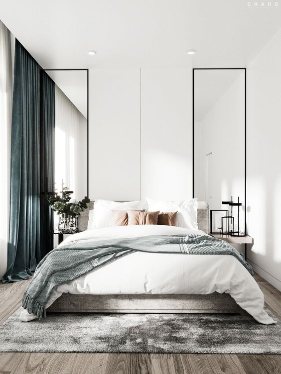 A light filled contemporary bedroom with tall mirrors, floating nightstands, a bed with neutral bedding and green curtains is pure chic