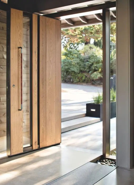a light-stained and glass pivot door with a handle is a lovely idea for a modern space, it makes the entrance cool