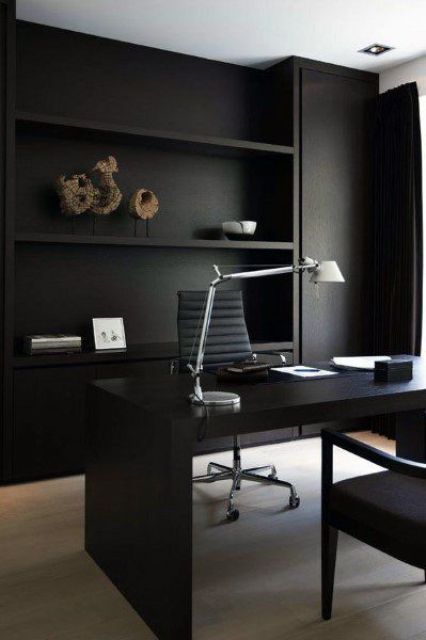 A sleek contemporary home office in black, with built in storage units and shelves, a black desk and a grey chair