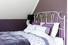 a small attic bedroom with a white forged bed, a purple paper lamp over the bed and purple and white bedding is cozy