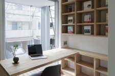a small contemporary home office with open stained storage units, a built-in desk, a black chair and a glazed wall for a view