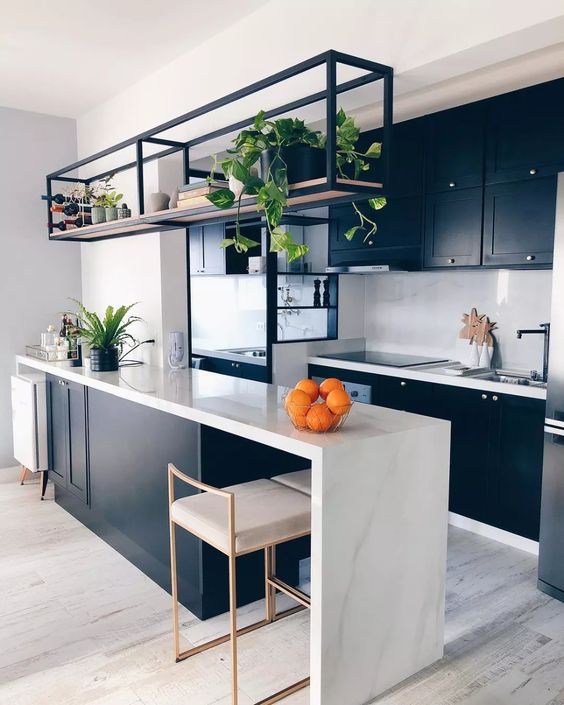 a stylish contemporary kitchen with black cabinetry, alarge kitchen island with a waterfall countertop, a black metal shelf and black fixtures