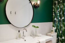 a stylish modern bathroom with a green accent wall, a floating light stained vanity, a round mirror and a tropical print curtain