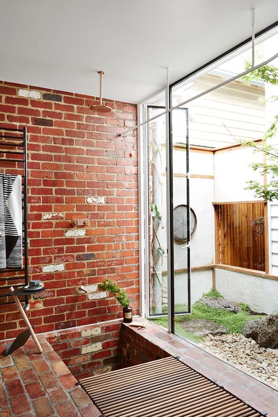 a sustainable bathroom with exposed brick walls and a floor, a wooden slab mat and metal framing is a cool space with style
