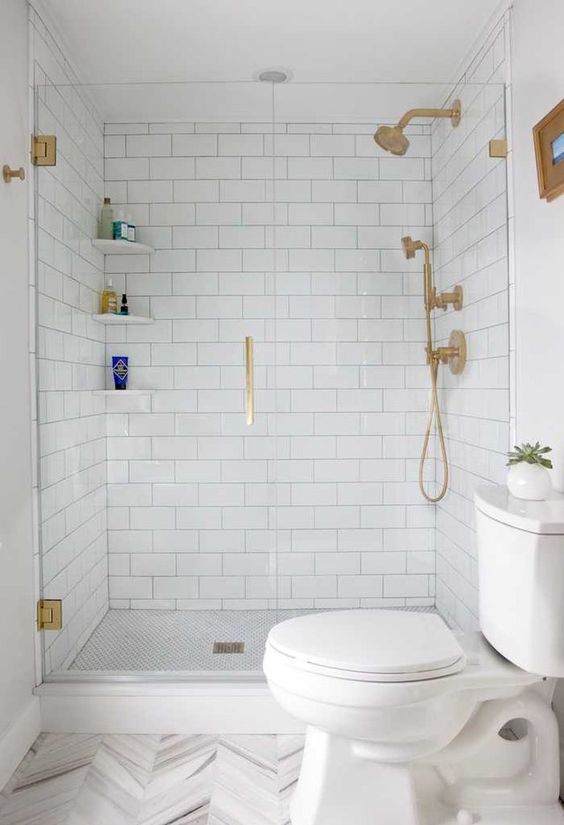 A white bathroom with subway and chevron tiles, gold fixtures and white appliances is a stylish idea that always works