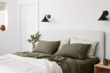 11 a pretty bedroom with a neutral upholstered bed, green and neutral bedding, nightstands, black sconces and potted greenery