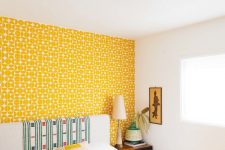17 a bright bedroom with a yellow printed wallpaper wall, a neutral bed with a statement headboard and a yellow blanket, a pretty artwork is chic