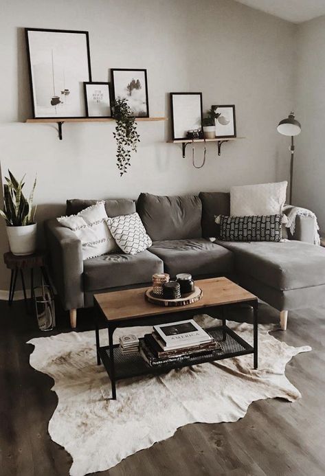 a light grey living room with a taupe sectional, a mini gallery wall, potted plants, an animal skin rug and a small coffee table