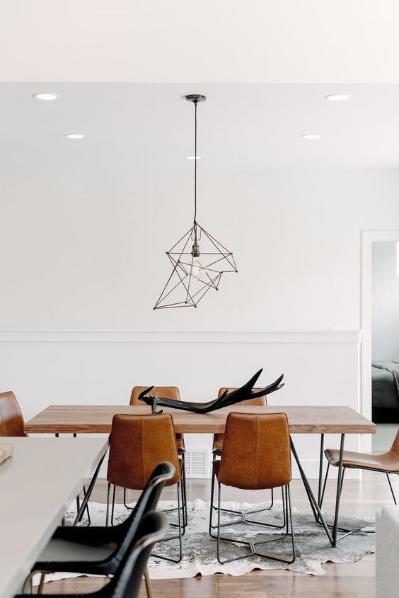 a beautiful contemporary dining space with a hairpin leg table, leather chairs, a catchy geometric pendant lamp is wow