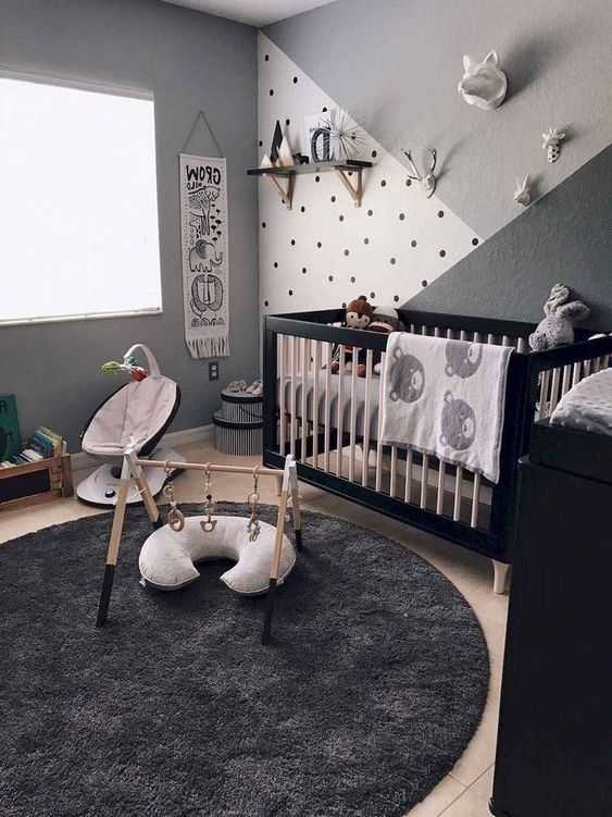 a black, grey and white nursery with a black and white crib, a black dresser, some baby furniture, shelves and toys is very cool