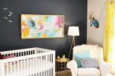 a bold nursery with a black accent wall, a striped rug and printed pillows, a pink stool and a bright artwork plus faux taxidermy is amazing