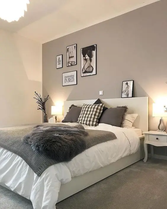 a catchy modern bedroom with a taupe accent wall, a creamy bed with taupe and white bedding, a small gallery wall