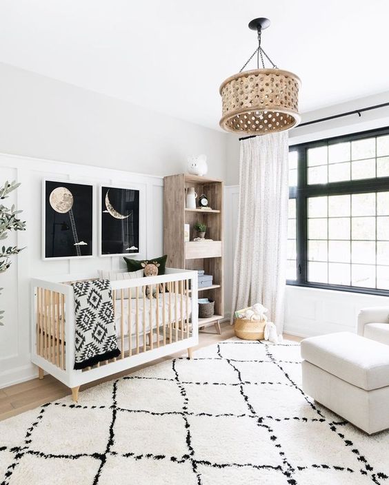a chic modern nurseyr in black and white, with a black framed window, a stained crib, a stained storage unit, a creamy chair, printed textiles and a wooden pendant lamp