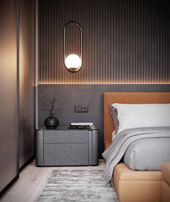 A chic taupe bedroom with a slab accent wall, an amber leather bed, a dark taupe nightstand, built in lights and pendant lamps