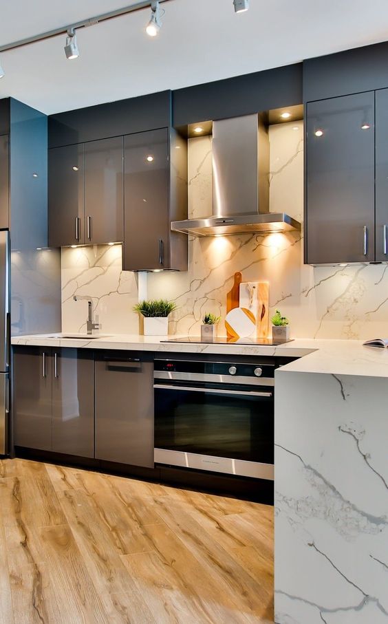 A chic taupe kitchen with glossy cabinets, a white marble tile backsplash and countertops, built in appliances is a bold idea to try