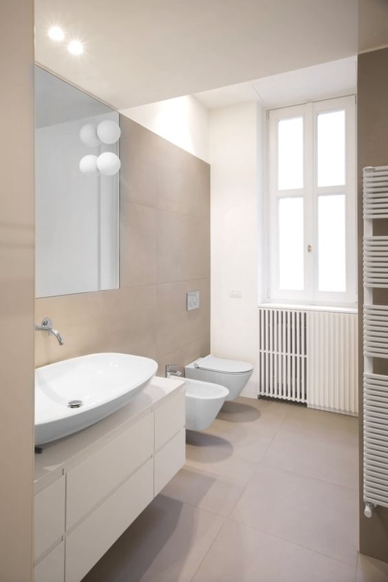 a contemporary bathroom clad with taupe tiles, a white floating vanity, white appliances and cool bubble lamps is cool