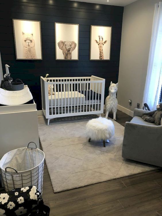 a contrasting nursery with a black plank accent wall, a white crib and changing table, a grey chair, pretty toys and a print gallery wall
