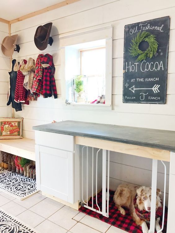 a farmhouse entryway with a built-in bench and a built-in dog kennel with a plaid cushion and a black countertop to use it as a table