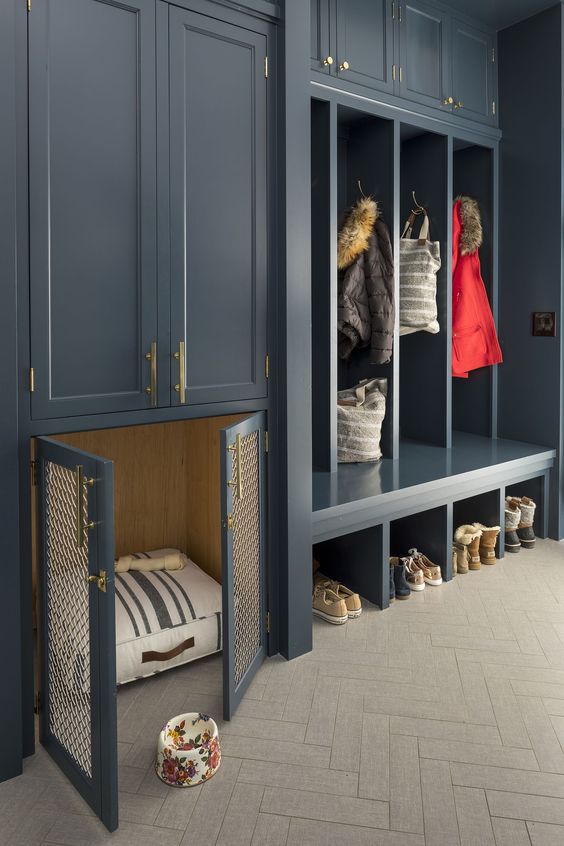 A graphite grey entryway with open and closed storage units and with a built in dog kennel with a striped mattress
