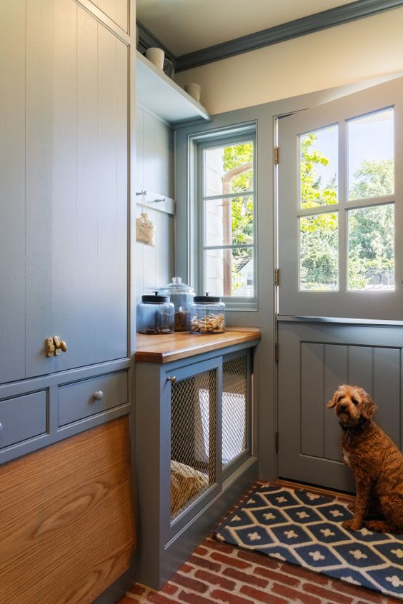 a grey entryway with elegant cabinetry and shelves plus a dog kennel with a mattress and a sliding door and an exit outside