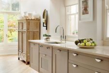 a lovely taupe kitchen with shaker cabinets, vintage knobs, white stone countertops and a vintage rustic cupboard for storage