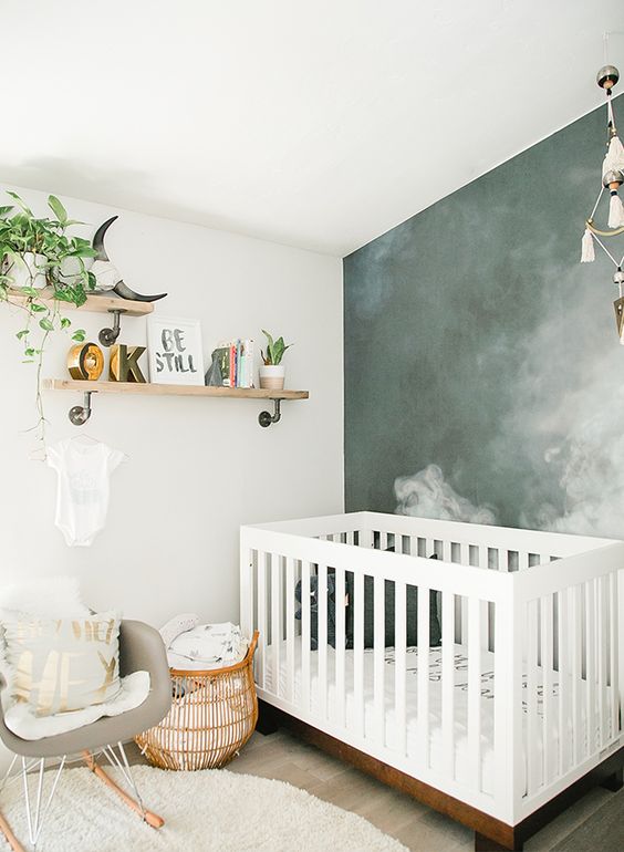 a modern small nursery with a grey chair, a white crib, open shelves, a smoke accent wall, a rattan basket for storage is amazing