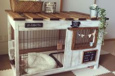 a pretty whitewashed dog kennel with a cushion, a bowl with water, use for storage on top and decorated with bunting