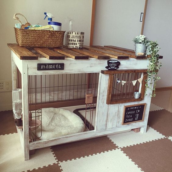 a pretty whitewashed dog kennel with a cushion, a bowl with water, use for storage on top and decorated with bunting
