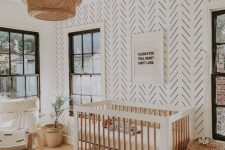 a welcoming boho nursery with a printed wall, white and stained furniture, a cactus basket for storage, neutral textiles and a woven pendant lamp