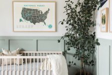 a welcoming nursery with green paneling on the wall, a stained nursery, a map, a statement plant and printed textiles is cool