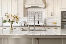 a white vintage kitchen with shaker cabinets, a white tile backsplash and white countertops, a taupe kitchen island with a white countertop