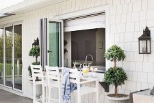 07 a lovely coastal outdoor dining space wiht a pass through window, tall white stools and a floating table, which is a windowsill