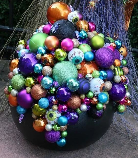 a Halloween decoration of a black cauldron and lots of colorful Christmas ornaments and eyeballs is bold and lovely