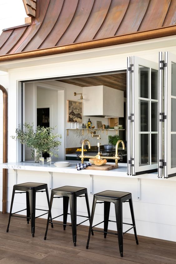 a pretty farmhouse space with a large French folding window, a floating table and black stools is a lovely solution