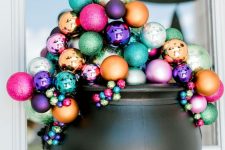 19 a lovely front door decoration of a cauldron filled with colorful Christmas ornaments is a gorgeous alternative to a usual Halloween wreath
