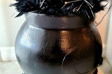 20 a lovely Halloween decoration of a black cauldron with feathers and lights, black firewood is a cool solution you can DIY