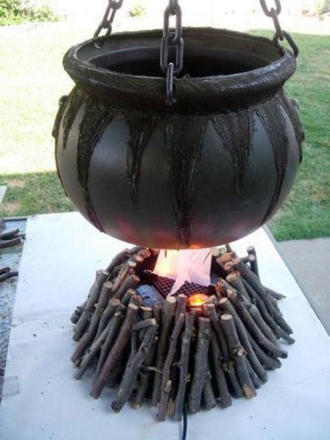 an outdoor Halloween decoration of a witch cauldron with branches under it and some candles is an easy decoration to go for