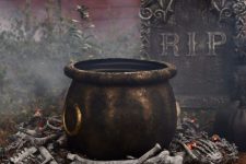 25 a realistic witches’ cauldron with faux bones under it and a tombstone for cool and bold Halloween decor that can be realized fast