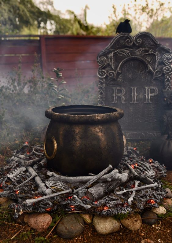 a realistic witches' cauldron with faux bones under it and a tombstone for cool and bold Halloween decor that can be realized fast