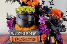 27 a whimsy Halloween decoration of vintage books, bold and dark blooms and leaves, a witch, a cauldron and some more stuff