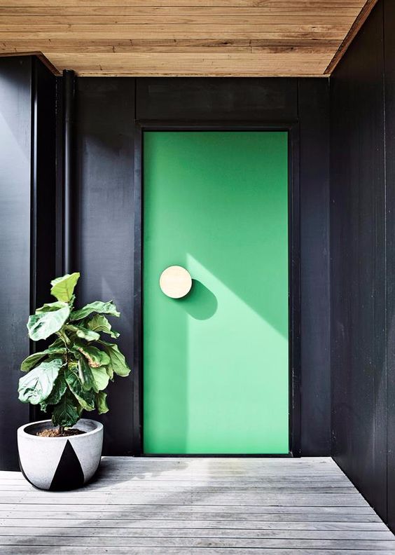 a black entrance with a whitewashed deck and an apple green front door accented with a large round white knob