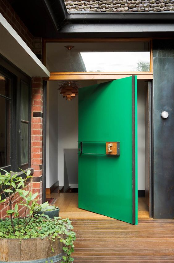 a bold green oversized aquare pivot front door is a creative solution for a modern home, it will make a statement both with its color and design