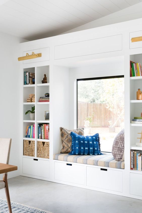 a bright contemporary reading nook with an upholstered bench, drawers and built-in shelves