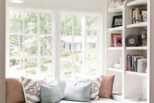 a cozy reading nook by the window – an upholstered bench with pillows and some shelves built in here and there