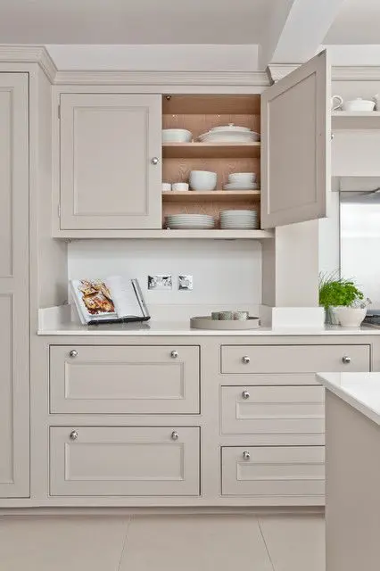 a delicate greige kitchen with shaker cabinets, white stone countertops and a matching sleek backsplash, simple knobs is a lovely idea