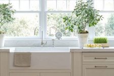 a delicate greige kitchen with shaker cabinets, white stone countertops, vintage fixtures and a window row as a backsplash is subtle and pretty