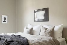 a greige bedroom with a large bed, lightweight nightstands, a beautiful pendant lamp and some lovely black and white artworks